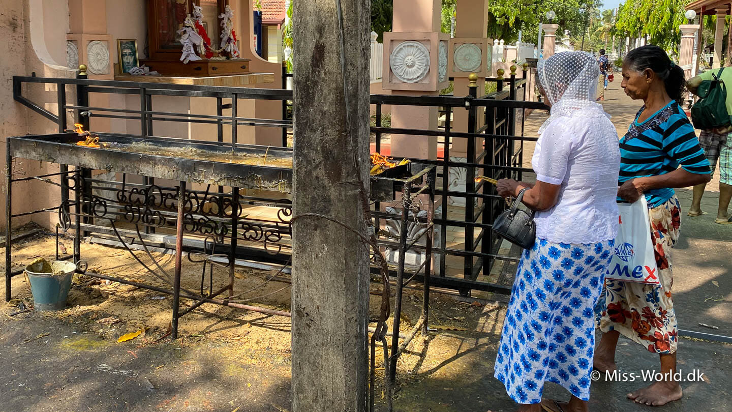To srilankanske kvinder tænder stearinlys ved den katolske kirke i Negombo