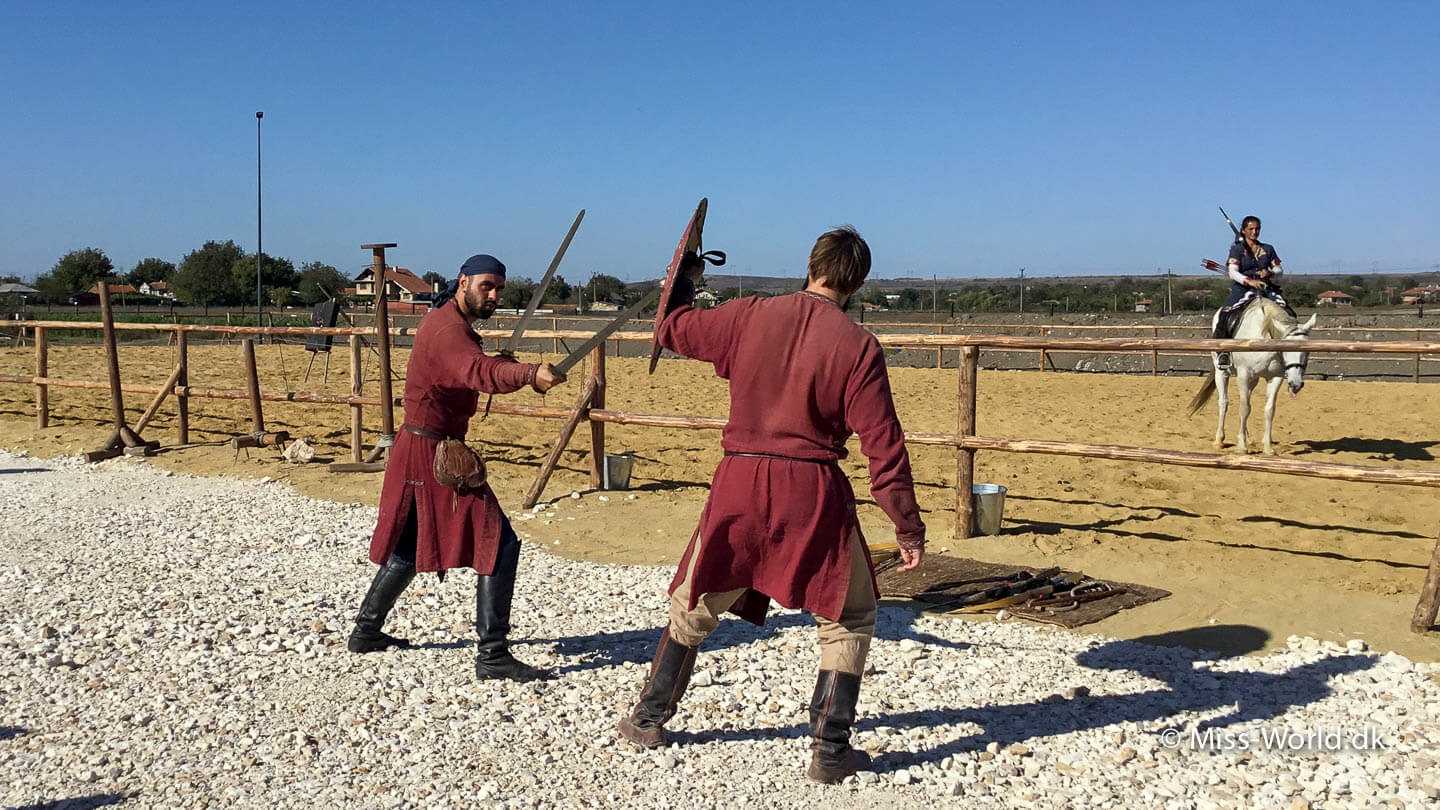 Krigere i beklædning fra middelalderen demonstrerer kampteknikker i en duel med sværd i den historiske Park i Bulgarien