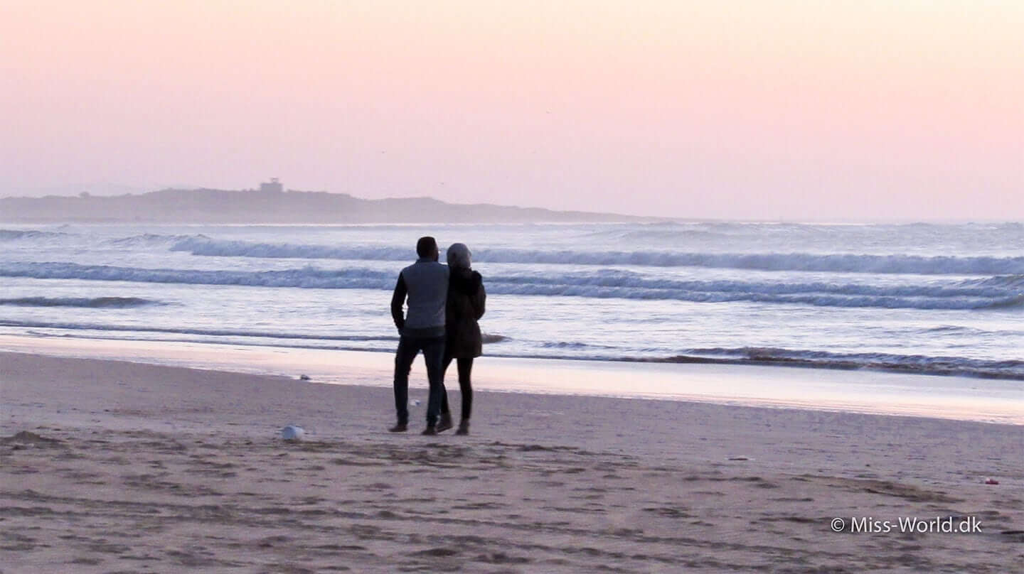 Romantosk ferie i Marokko. Par på stranden i solnedgang